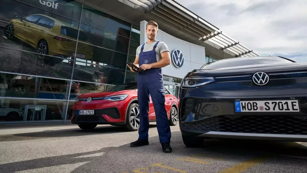 Volkswagen monteur staat buiten voor een showroom met een tablet in de handtussen ID. modellen 