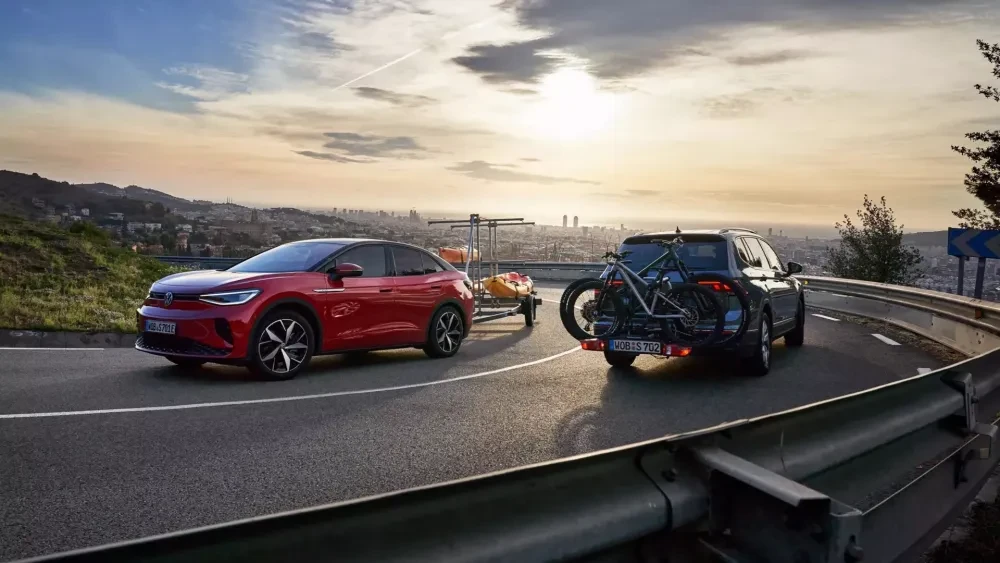 Twee Volkswagens rijden naast elkaar, eentje heeft een aanhanger, de ander een fietsendrager