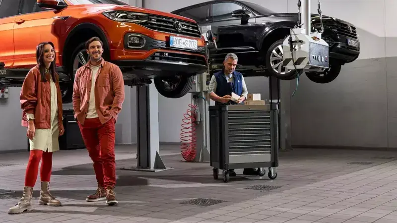 Stel wacht in de werkplaats op de Volkswagen monteur naast een Volkswagen