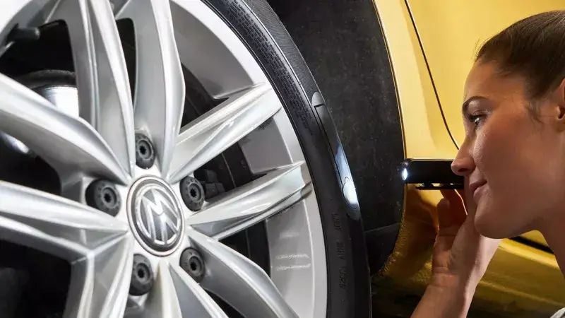 Volkswagen monteur bekijkt het profiel van een band