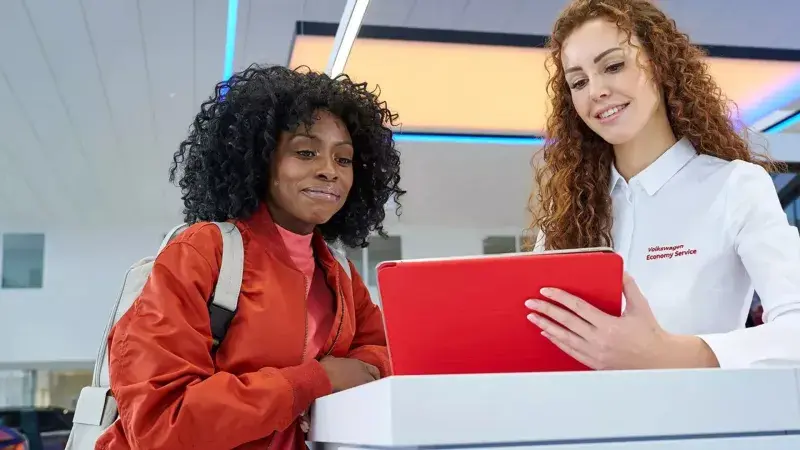 Volkswagen servicemedewerker laats iets zien aan een klant op de tablet bij de receptie