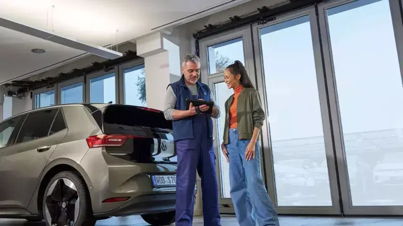 Een monteur en een vrouw staan voor een Volkswagen ID.3