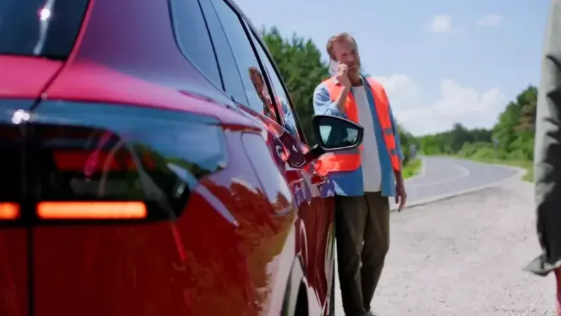 Man met veiligheidshesje aan staat te bellen naast een Volkswagen