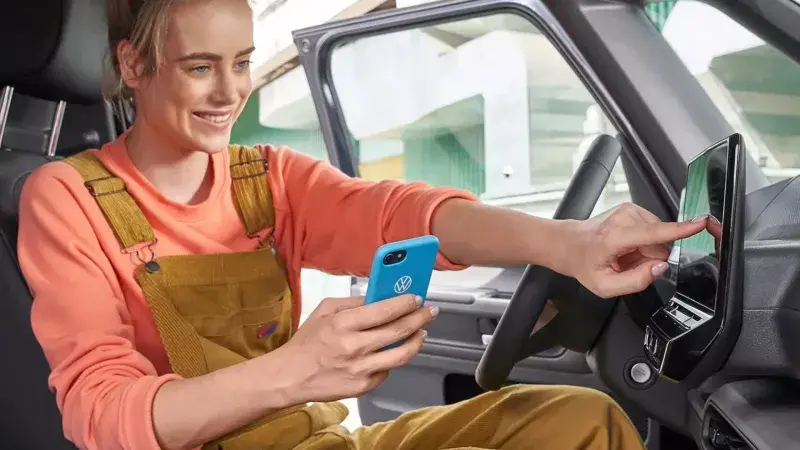 Vrouw koppelt telefoon aan de auto zittend in de auto