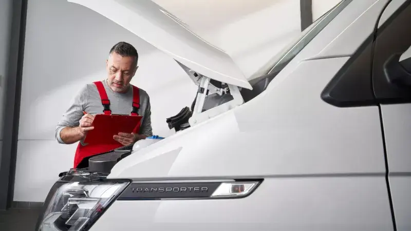Monteur bij een Volkswagen Transporter met open motorkap